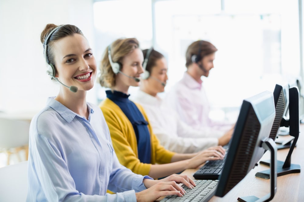 a group of people sitting at a desk with headsets on