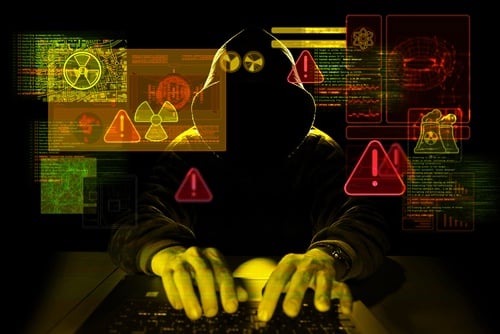 a person in a hooded jacket typing on a laptop